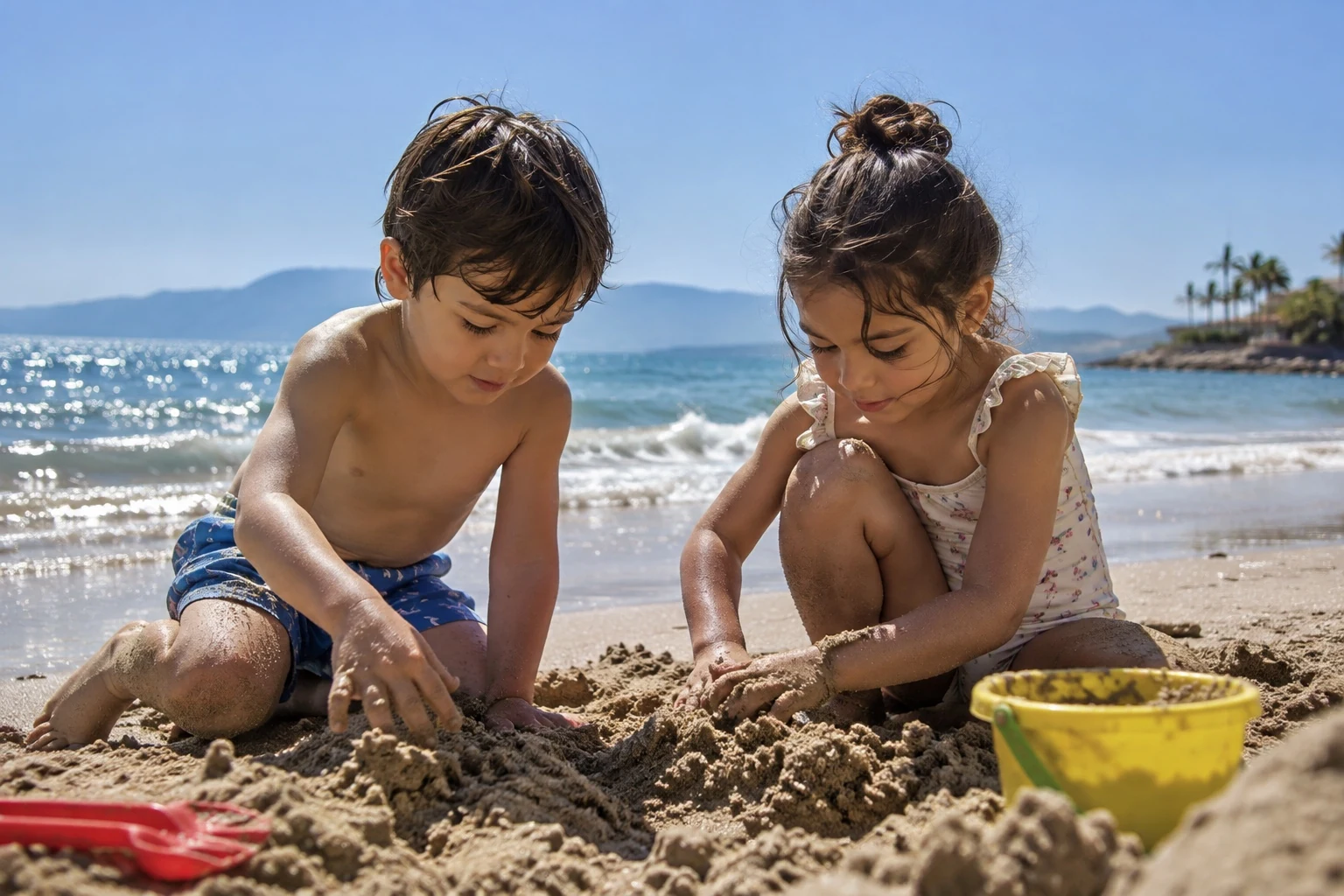 Dos niños jugando con arena en la playa junto a las olas
